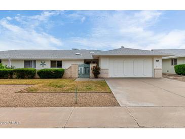 Charming single-story home with a two-car garage, manicured bushes, and small decorative entry gate at 12939 W Prospect Dr, Sun City West, AZ 85375