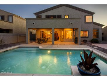 Relaxing backyard pool with covered patio and outdoor seating, perfect for entertaining at twilight at 18346 W Sweet Acacia Dr, Goodyear, AZ 85338
