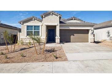 Charming single-story home with a tan exterior, front yard landscaping, and a two-car garage at 25364 W Sunland Ave, Buckeye, AZ 85326