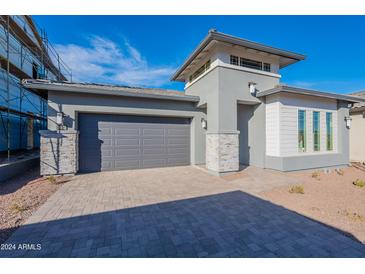 Beautiful single-story home featuring a gray exterior, gray garage door, desert landscaping and a paver driveway at 21422 W Meadowbrook Ave, Buckeye, AZ 85396