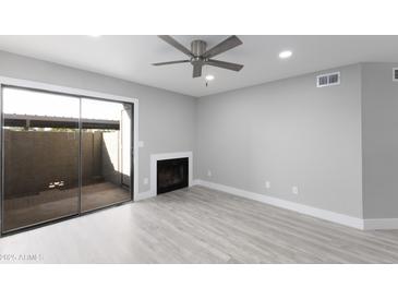 Bright living room with sliding glass door, fireplace, and modern ceiling fan at 533 W Guadalupe Rd # 1068, Mesa, AZ 85210