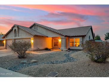 Charming single-story home featuring desert landscaping, warm exterior lighting and a tile roof at 5830 W Cinnabar Ave, Glendale, AZ 85302