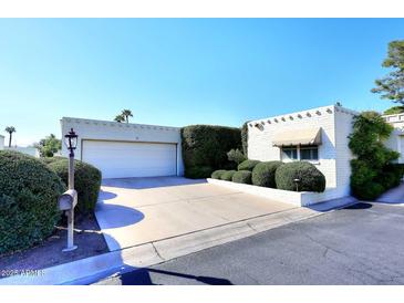 Charming single-story home features a clean white facade, manicured landscaping, and a convenient two-car garage at 25 E San Miguel E Ave, Phoenix, AZ 85012