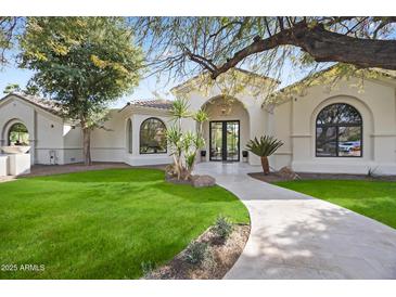 Inviting home exterior with lush lawn, tiled walkway, and arched entryway providing curb appeal at 7157 E Bronco Dr, Paradise Valley, AZ 85253