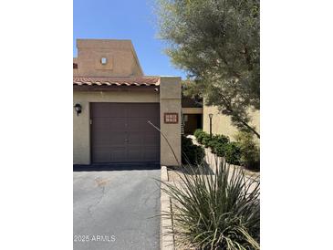 Beige townhome with brown garage door, red tile roof, and tidy landscaping at 8302 N 21St Dr # L204, Phoenix, AZ 85021