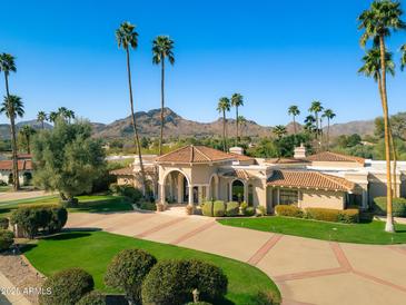 Stunning aerial view of a luxury estate home with lush landscaping, circular drive and mature palm trees at 8712 N 64Th Pl, Paradise Valley, AZ 85253