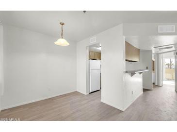 Bright dining room with light wood floors and a view into the kitchen with white refrigerator at 12123 W Bell Rd # 241, Surprise, AZ 85378