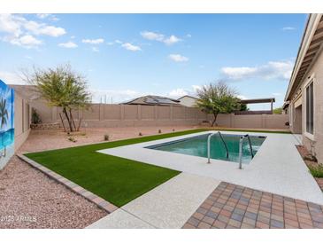 Beautiful backyard featuring a sparkling pool, lush artificial grass, and desert landscaping for low maintenance appeal at 23800 N 169Th Ave, Surprise, AZ 85387