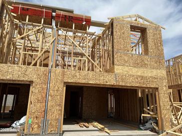 Two-story home under construction, featuring wood framing and a garage, set against a bright, partly cloudy sky at 5848 E Covey Ln, Phoenix, AZ 85054