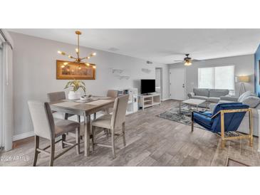 Open-concept living and dining area with wood-look floors and modern chandelier at 8760 W Meadow Dr, Peoria, AZ 85382