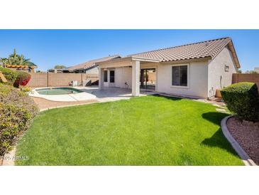 Inviting backyard featuring a well-maintained lawn, covered patio, and a sparkling pool for relaxation at 15412 N 160Th Ln, Surprise, AZ 85374