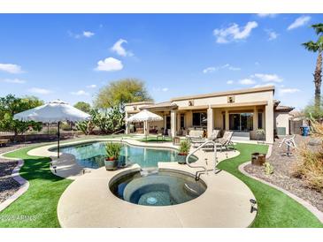 Inviting backyard pool area with a spa, lush landscaping, and patio seating at 21141 E Stirrup St, Queen Creek, AZ 85142