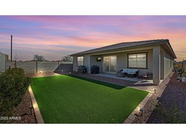 Home backyard featuring drought tolerant rock landscaping, modern lighting and artificial turf at 17286 W Running Deer Trl, Surprise, AZ 85387