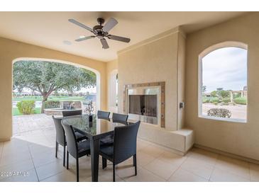Covered patio featuring a dining table, outdoor fireplace, ceiling fan and scenic golf course views at 623 E Peach Tree St, Queen Creek, AZ 85140