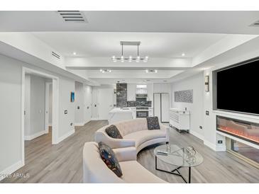 Bright living room featuring modern lighting, fireplace, television and an open floorplan flowing into the kitchen at 7151 E Rancho Vista Dr # 1003, Scottsdale, AZ 85251