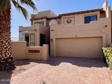 A two-story stucco home features a two-car garage, red brick driveway, and lush desert landscaping at 7955 E Chaparral Rd # 34, Scottsdale, AZ 85250