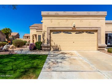 Tan home exterior featuring a well-manicured front lawn and a two-car garage at 8850 W Piute Ave, Peoria, AZ 85382