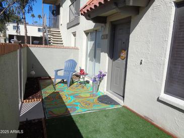 Inviting front door entrance with charming decor and colorful outdoor rug on an artificial turf covered patio at 14259 N Oakwood W Ln, Fountain Hills, AZ 85268