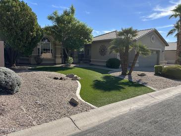 Charming single-story home with lush landscaping, including palm trees, gravel, and artificial grass at 15385 W Indianola Ave, Goodyear, AZ 85395