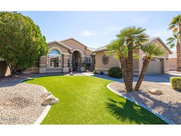 Beautiful single-story home with desert landscaping, artificial turf, palm trees, and neutral exterior paint at 15385 W Indianola Ave, Goodyear, AZ 85395