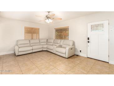 Cozy living room features tile floors, a ceiling fan, and a comfortable sectional sofa at 6842 N 10Th Pl, Phoenix, AZ 85014