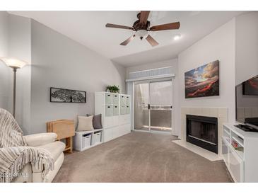 Inviting living room features a fireplace, ceiling fan, and sliding glass doors to the balcony at 10410 N Cave Creek Rd # 1078, Phoenix, AZ 85020