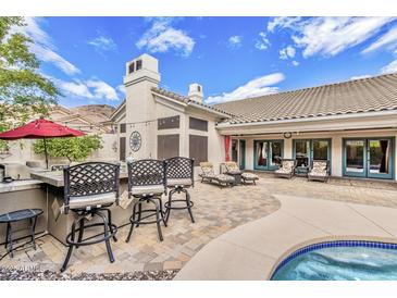Outdoor living space featuring bar seating, lounge chairs, and a sparkling pool with a lush desert landscape at 14244 N 14Th Pl, Phoenix, AZ 85022