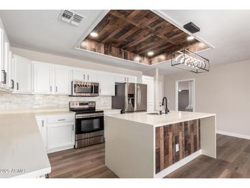 Bright kitchen features stainless appliances, a wood paneled island, and a decorative wood paneled inset in the ceiling at 2149 S Olivewood --, Mesa, AZ 85209