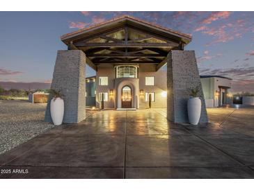 Striking home featuring a porte-cochere with stone pillars and desert landscaping at twilight at 29501 N 76Th St, Scottsdale, AZ 85266