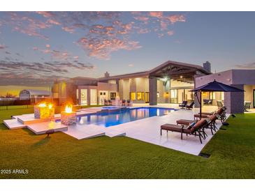 Resort-style backyard with luxurious pool, lounge chairs, fire pit, and lush green lawn at 29501 N 76Th St, Scottsdale, AZ 85266