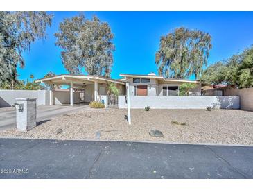 Charming single-story home with a covered carport, desert landscaping, and a privacy wall in a sunny setting at 520 W Gibraltar Ln, Phoenix, AZ 85023