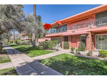 Charming two-story pink condo building with landscaped front yard and red umbrellas on the balcony at 146 E Coronado Rd # 39, Phoenix, AZ 85004