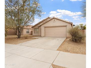 Tan single story home featuring a two car garage, desert landscaping, and a concrete driveway at 2323 W Carson Rd, Phoenix, AZ 85041