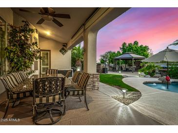Covered outdoor patio with dining area, stone columns, and views of the pool and landscaped backyard at 11336 N 117Th Way, Scottsdale, AZ 85259