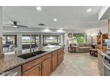 Bright kitchen with granite countertops and a breakfast bar overlooking the living area at 12822 W Ballad Dr, Sun City West, AZ 85375