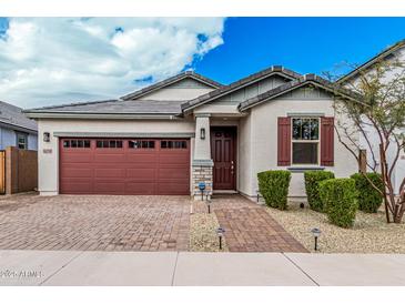 Charming single-story home boasts a brick driveway, two-car garage and well-manicured landscaping at 14254 W Honeysuckle Dr, Surprise, AZ 85387