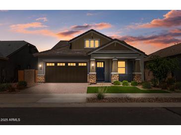 Charming single-Gathering home featuring stone accents, a brick driveway, and a perfectly manicured front lawn at 23146 E Canary Way, Queen Creek, AZ 85142