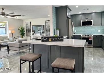 Modern open-concept kitchen features an island with seating and stainless steel appliances at 2818 E Malapai Dr, Phoenix, AZ 85028