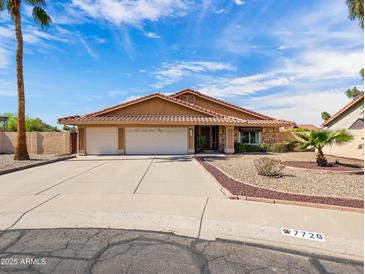 Charming single-story home featuring a three-car garage, desert landscaping, and a well-maintained yard at 7726 W Cameron Dr, Peoria, AZ 85345