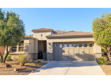 Charming single-story home featuring a well-manicured yard and a two-car garage with decorative windows at 13068 W Mine Trl, Peoria, AZ 85383