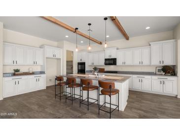 Bright kitchen features white cabinets, wood beams, stainless steel appliances, and a large center island with bar seating at 22318 S 226Th Pl, Queen Creek, AZ 85142