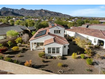 Aerial view of a home featuring solar panels, desert landscaping, and mountain views at 20701 W Minnezona Ave, Buckeye, AZ 85396