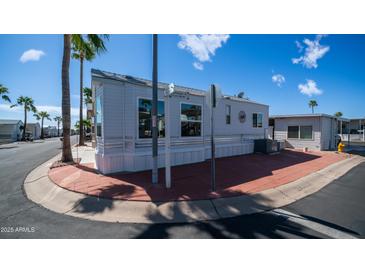 The exterior of this manufactured home boasts a corner lot and vibrant palm trees at 39 Iron Ore Dr, Apache Junction, AZ 85119