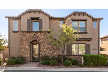 Charming two-story townhome featuring a stone facade, manicured landscaping, and a welcoming entrance at 1153 E Muirwood Dr, Phoenix, AZ 85048