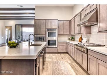 Spacious kitchen featuring a large island with a marble countertop and stainless steel appliances at 14455 N Adero Canyon Dr, Fountain Hills, AZ 85268