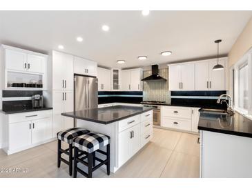 Modern kitchen with white cabinets, stainless steel appliances, an island, and sleek black countertops at 339 W Southern Hills Rd, Phoenix, AZ 85023