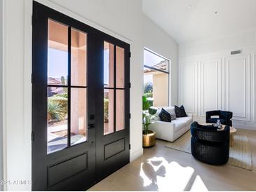Bright entryway with double glass doors leading into a modern living room with white walls and elegant furniture at 9238 E Palm Tree Dr, Scottsdale, AZ 85255