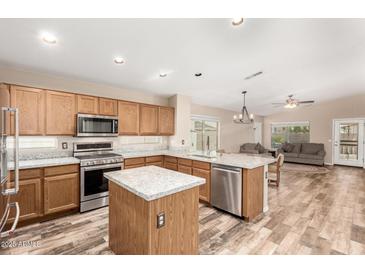 Well-equipped kitchen with stainless steel appliances, granite counters, and a center island at 11023 W Utopia Rd, Peoria, AZ 85373