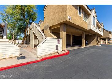 Exterior view of building with covered parking and stairs leading to upper units, set against a clear blue sky at 2035 S Elm St # 218, Tempe, AZ 85282