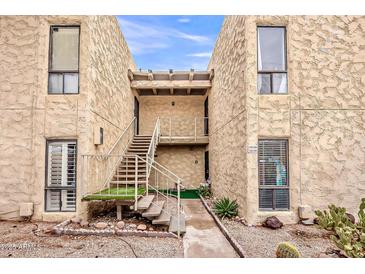 Building exterior showcasing a two-story tan facade with desert landscaping, stairs to the second level, and unit numbers at 4950 N Miller Rd # 231, Scottsdale, AZ 85251